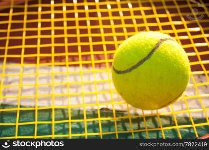 Tennis ball and racket. Yellow tennis nets. Behind the tennis courts.