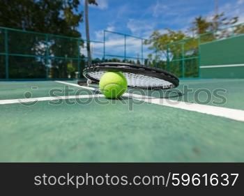 Tennis ball and racquet on court. Tennis ball and racquet on the court close-up