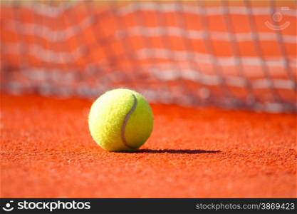 Tennis ball on a orange hard court &#xA;