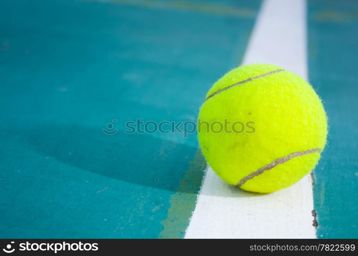 Tennis ball on the field. Tennis ball resting on a golf ball.