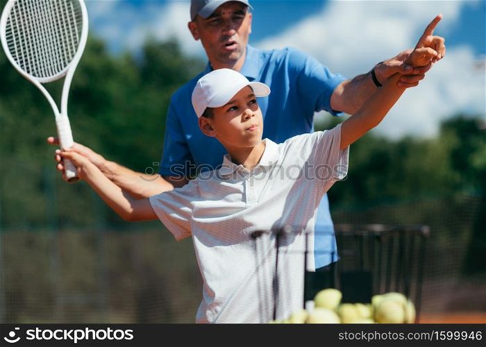Tennis Coach Practicing Service with Boy on Tennis Class Outdoors.. Tennis Instructor Practicing Service with Junior Athlete
