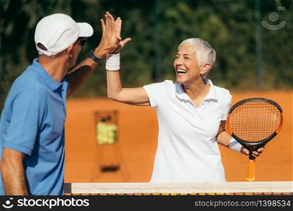 Tennis Coach Practicing Service with Senior Woman on Outdoor Tennis Class. Giving high five.