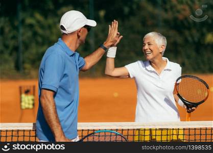 Tennis Coach Practicing Service with Senior Woman on Outdoor Tennis Class. Giving high five.