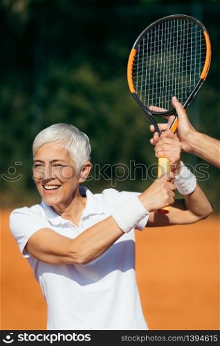 Tennis Instructor Teaching Elderly Woman How to Play Tennis