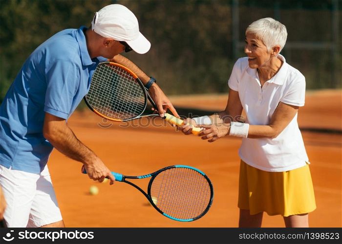 Tennis Instructor with Senior Woman in her 60s Having a Tennis Lesson on Clay Court.