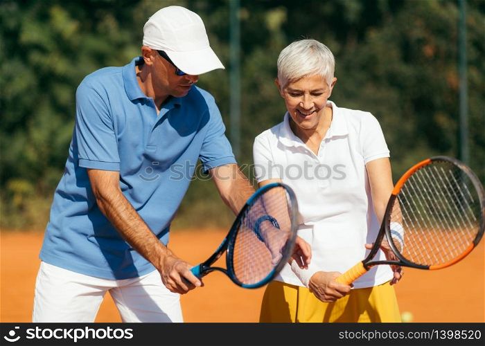 Tennis Instructor with Senior Woman on Clay Court. Woman having a Tennis Lesson.