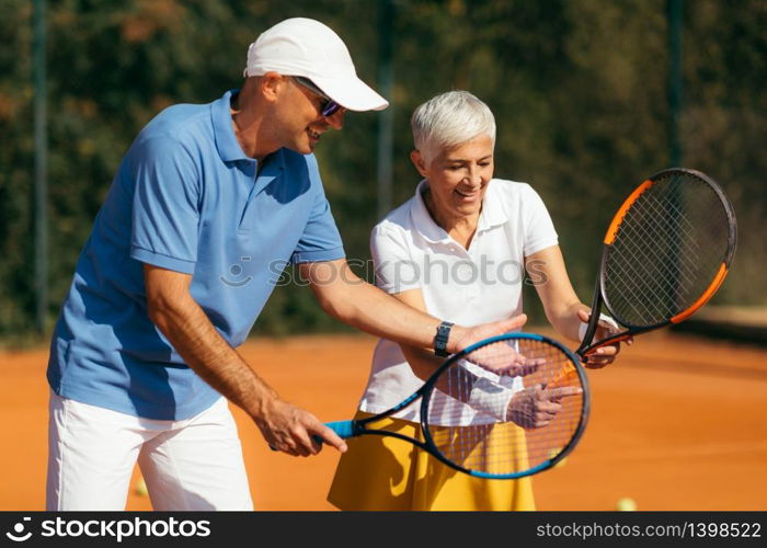 Tennis Instructor with Senior Woman on Clay Court. Woman having a Tennis Lesson.