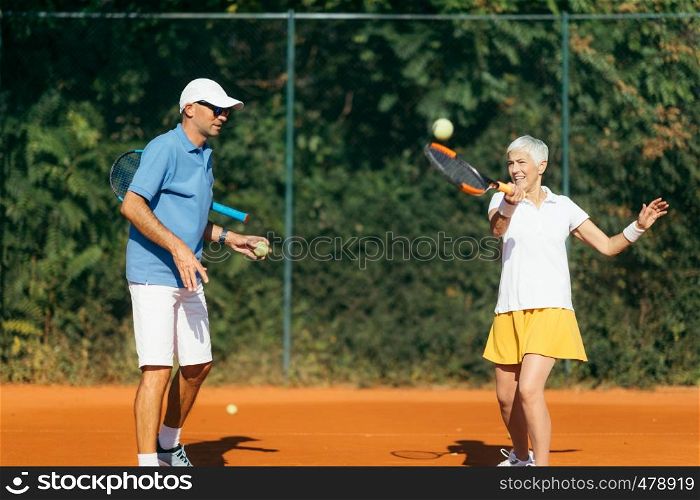 Tennis instructor with senior woman, tennis training lesson