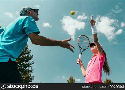 Tennis instructor with young girl on tennis training