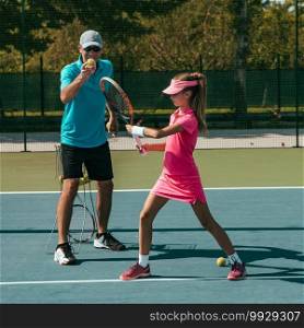 Tennis instructor with young girl on tennis training