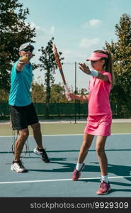 Tennis instructor with young girl on tennis training