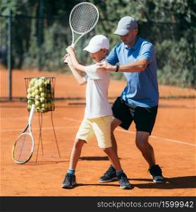 Tennis Instructor with Young Talent on Clay Court. Boy having a Tennis Lesson.. Tennis Lesson
