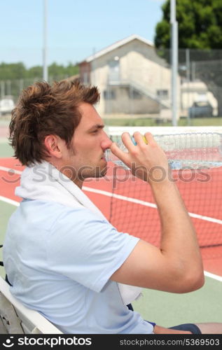 Tennis player drinking on the bench