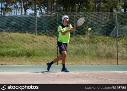 Tennis player hitting backhand at ball with racket on court.