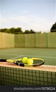 Tennis racket and balls on the net, nobody, outdoor court. Active healthy lifestyle, sport game concept. Tennis racket and balls on the net, outdoor court