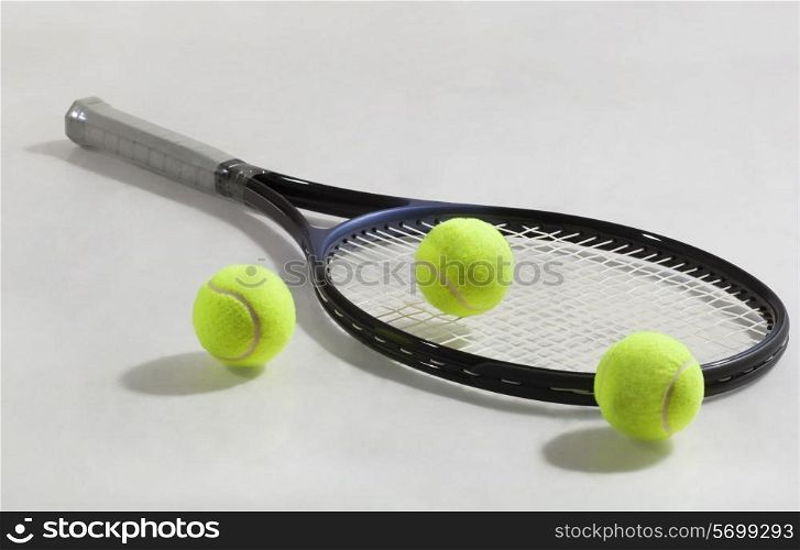 Tennis racket and tennis balls isolated over gray background