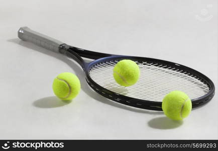 Tennis racket and tennis balls isolated over gray background