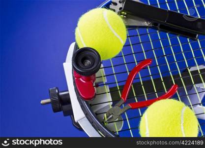 Tennis racket in stringing machine being repaired on blue background