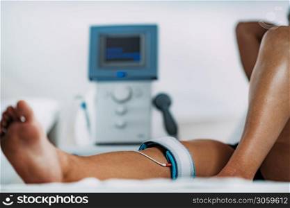TENS, Transcutaneous Electrical Nerve Stimulation in Physical Therapy. Therapist Positioning Electrodes onto Patient&rsquo;s Knee