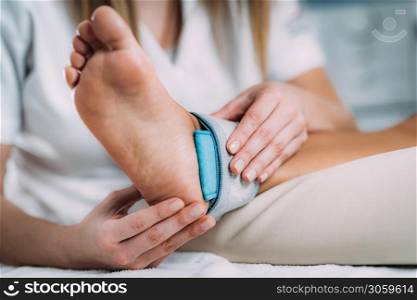 TENS, Transcutaneous Electrical Nerve Stimulation in Physical Therapy. Therapist Positioning Electrodes onto Patient&rsquo;s Ankle Joint. TENS, Transcutaneous Electrical Nerve Stimulation in Physical Therapy.