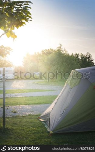 Tent and car on campsite. Sinrise back light
