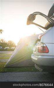 Tent and car on campsite. Sinrise back light