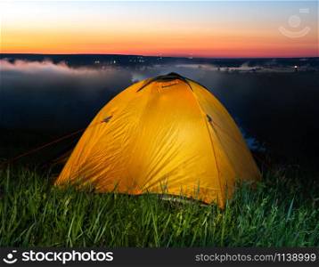 Tent in steppe near river at sunrise