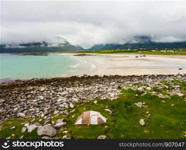 Tent on seashore in summer, cloudy hazy weather. Camping on ocean shore. Skagsanden Beach Flakstadoy Lofoten archipelago Norway. Holidays travel and adventure.. Tent on sea shore, Skagsanden Beach Lofoten Norway