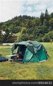 Tent with people inside standing on c&site. Family living in a tent spending summer vacation in mountains. C&life. Tent with people inside standing on c&site. Family living in a tent spending summer vacation in mountains