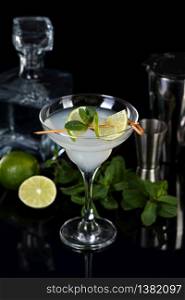 Tequila, Citrus liquor, lime juice - this is a Margarita cocktail. A of lime with a sprig of mint decorates a glass. Dark moody food