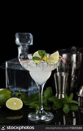 Tequila, Citrus liquor, lime juice - this is a Margarita cocktail. A of lime with a sprig of mint decorates a glass. Dark moody food
