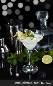 Tequila, Citrus liquor, lime juice - this is a Margarita cocktail. A  of lime with a sprig of mint decorates a glass. Dark  moody food
