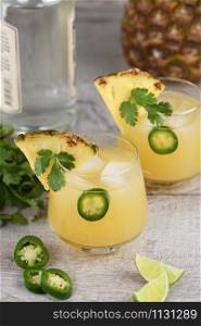 Tequila cocktail with pineapple juice, jalapeno slices and cilantro, cooled with ice