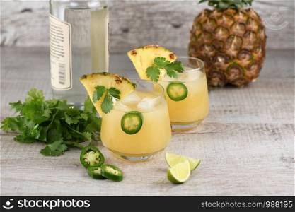 Tequila cocktail with pineapple juice, jalapeno slices and cilantro, cooled with ice