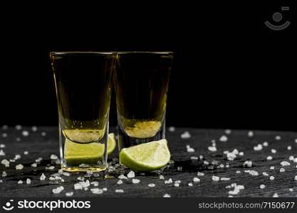 tequila is poured into two glasses and salt and lime