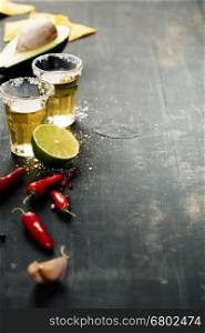 Tequila shots and mexican ingredients on rustic table
