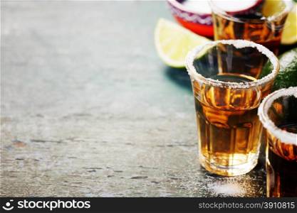 Tequila shots with lime and salt on rustic background