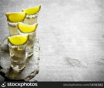 Tequila shots with lime and salt . On the stone table.. Tequila shots with lime and salt .