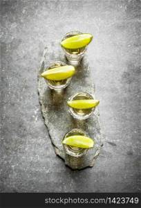 Tequila shots with lime and salt . On the stone table.. Tequila shots with lime and salt .