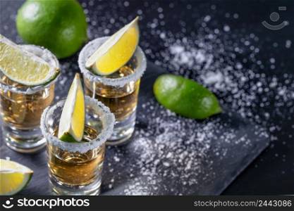 Tequila with lime on a dark table with sprinkled salt. Tequila with lime on dark table with sprinkled salt