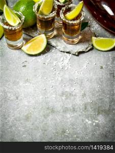 Tequila with salt and lime slices. On the stone table.. Tequila with salt and lime slices.
