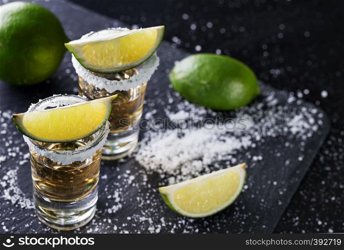 Tequila with sliced and whole lime and salt on a black background. Alcoholic cocktail. Mexican traditional drink. Tequila with sliced and whole lime and salt