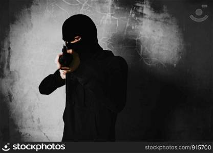Terrorist shooting with his war gun weapon with in abandoned building background. Criminal and Dangerous illegal people concept. Terrorist and war theme. Dark tone and high contrast use