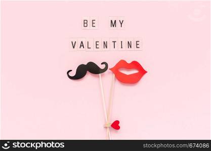 Text Be my Valentine and couple paper mustache, lips props fastened clothespin heart on stick on pink paper background. Concept Valentine's Day, Valentine card Top-down composition Creative flat lay.. Text Be my Valentine and couple paper mustache, lips props fastened clothespin heart on stick on pink paper background. Concept Valentine's Day, Valentine card Top-down composition Creative flat lay