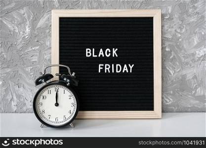 Text Black friday on black letter board and alarm clock on table against grey stone background. Concept Black friday , season sales time.. Text Black friday on black letter board and alarm clock on table against grey stone background. Concept Black friday , season sales time
