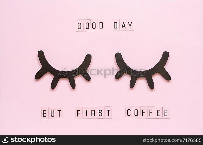 Text Good day, but first coffee and decorative wooden black eyelashes, closed eyes, on pastel pink paper background. Layout Top view Flat lay Concept good morning Template for postcard or design.. Text Good day, but first coffee and decorative wooden black eyelashes, closed eyes, on pastel pink paper background. Layout Top view Flat lay Concept good morning Template for postcard or design