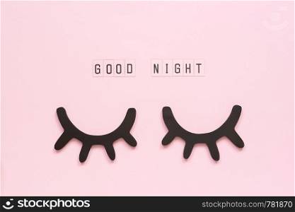 Text Good Night and decorative wooden black eyelashes, closed eyes on pink paper background. Concept Sweet dreams Greeting card Top view Creative flat lay.. Text Good Night and decorative wooden black eyelashes, closed eyes on pink paper background. Concept Sweet dreams Greeting card Top view Creative flat lay