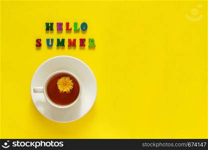 Text Hello summer, ?up of tea with dandelion, Still life on yellow background. Copy space, Flat lay, Top view concept