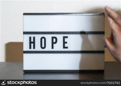 Text hope nad crossed fingers. Concept for hope,  salvation and luck. White illuminated board.