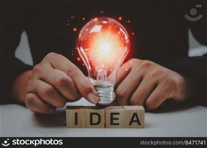 Text idea with a hand holding a light bulb Innovative wood cube block solution.. Text idea with a hand holding a light bulb Innovative wood cube block solution